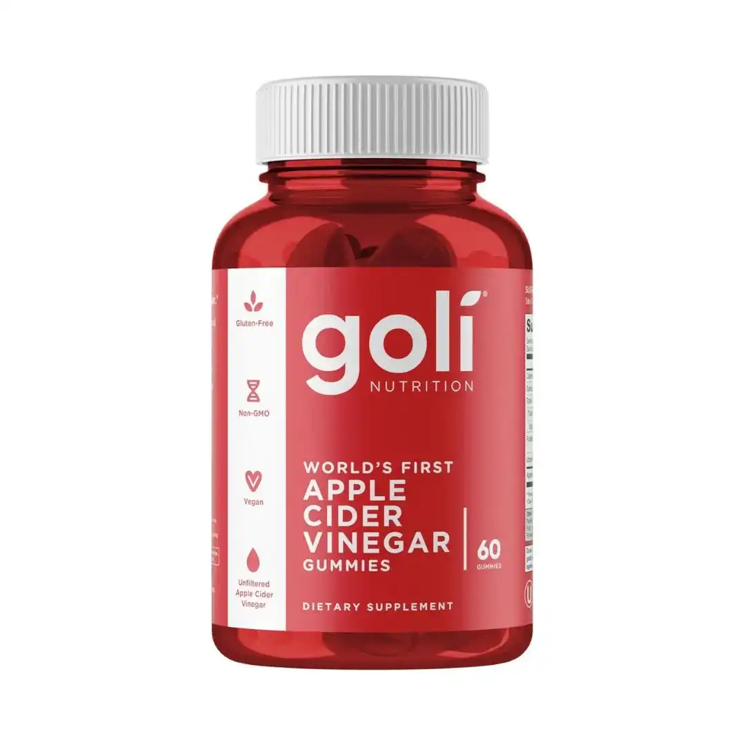 Bottle of Goli Apple Cider Vinegar Gummy Vitamins B12 with red gummies spilled on a table