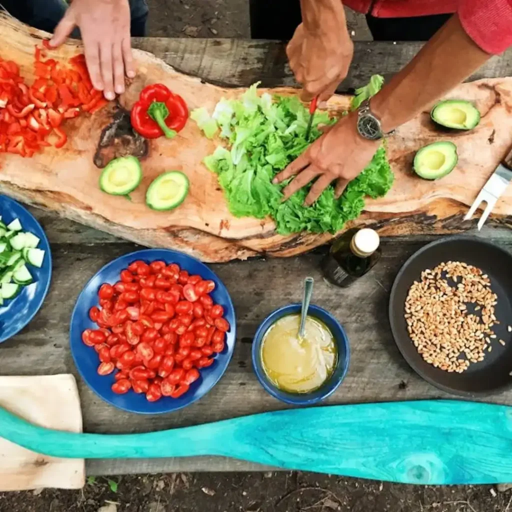 Person preparing a plant-based meal with fresh vegetables, grains, and legumes on a wooden counter